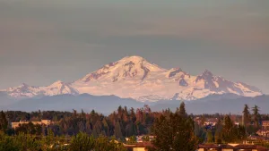 Scenic landscape view of Langley, BC residential neighborhoods with the snow-capped Mount Baker visible in the background at sunset.