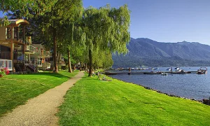 Scenic view of a lakeside pathway and vacation homes at Cultus Lake in Chilliwack on a sunny day.